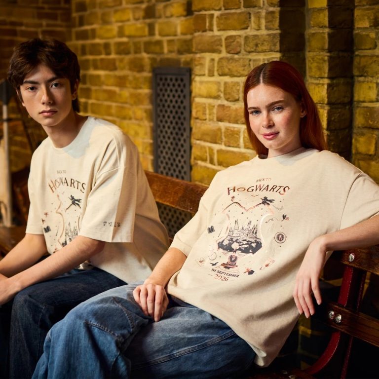 Two models wearing the oatmeal Back to Hogwarts 2026 T-shirt printed with a crest-shaped Hogwarts Castle graphic and the 1st September 2026 date
