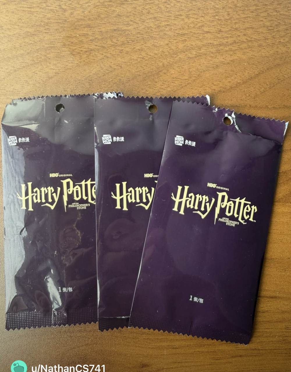 Three sealed purple Kakawow Harry Potter TV series card packs on a wooden table